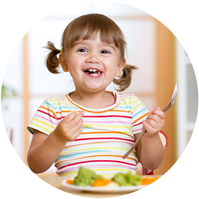Happy toddler in colorful striped shirt smiling at mealtime with healthy food.