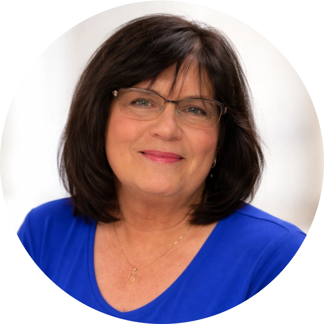 Professional headshot of woman with dark hair and glasses wearing blue shirt against white background.