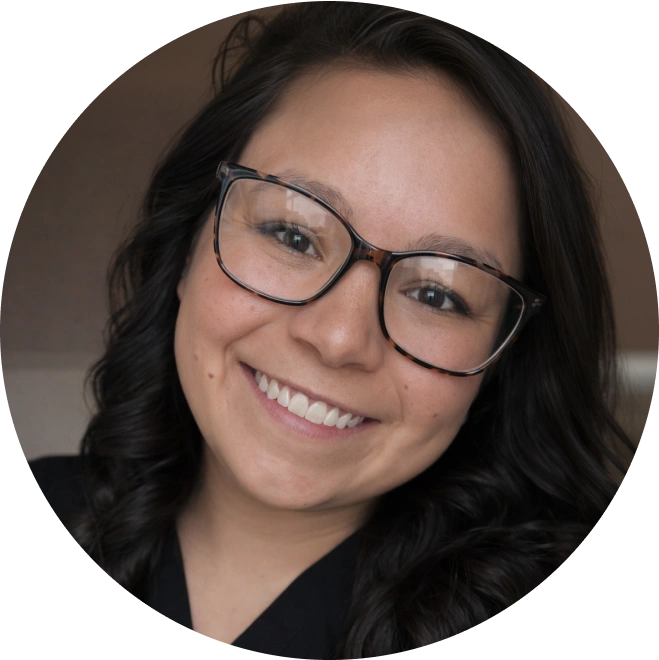 Woman wearing glasses smiling at camera in professional headshot for pediatric dentistry practice.