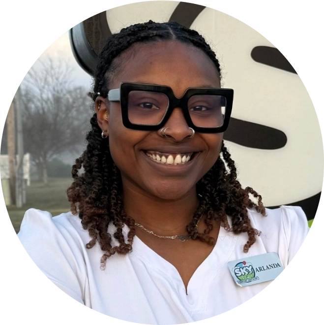 Young woman wearing glasses smiling at camera in pediatric dental office setting