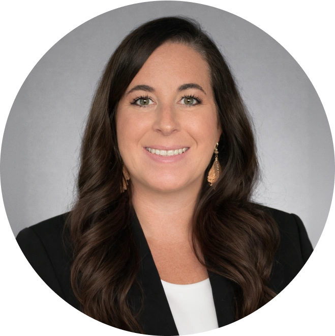 Professional headshot of woman in black blazer against gray background for dental practice.