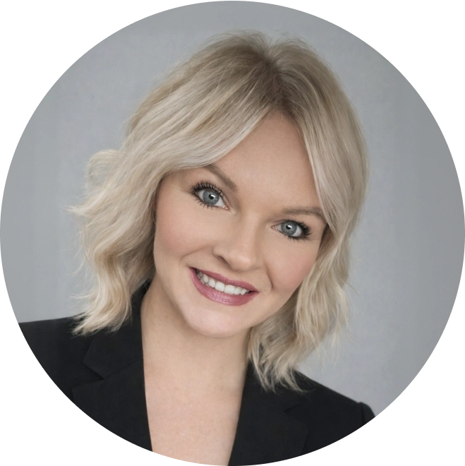 Professional headshot of a blonde woman smiling in a black blazer against gray background.