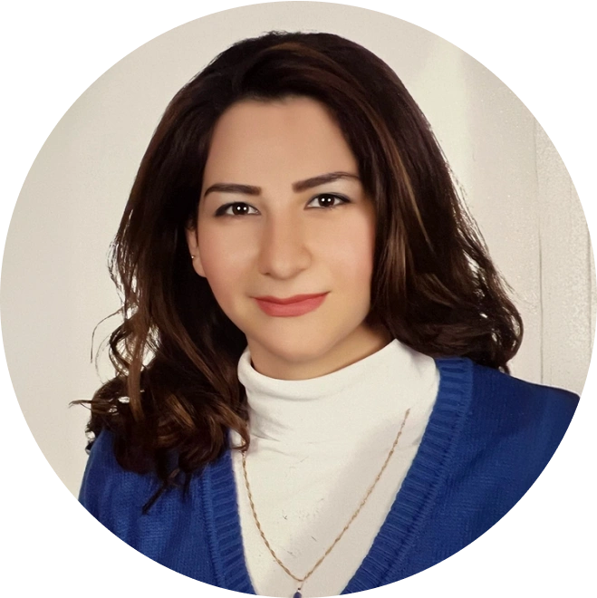 Professional portrait of a woman wearing a blue cardigan over a white turtleneck against a neutral background.