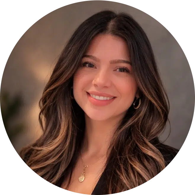 Professional headshot of a woman with long dark hair smiling at camera against neutral background.