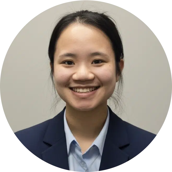 Professional headshot of smiling woman in navy blazer and light blue shirt against neutral background.