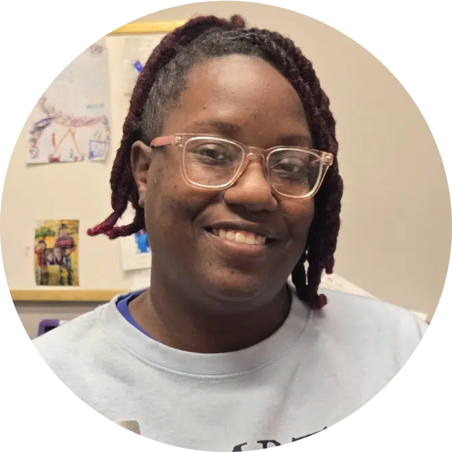Smiling staff member wearing glasses in dental office setting at Sky Pediatric Dentistry