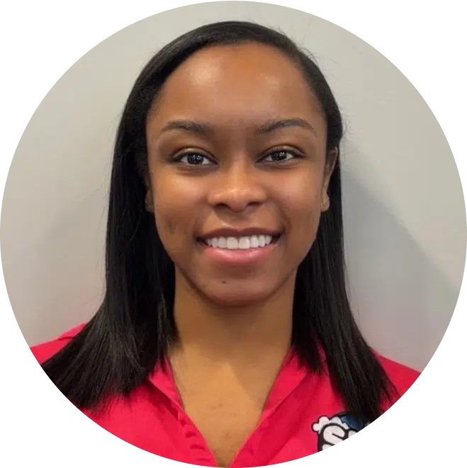 Professional headshot of smiling female dental staff member wearing pink scrubs against neutral background.